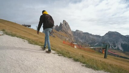 Wall Mural - Man traveler walks to the famous Mount Seceda in the Dolomites. Mountain trail in Alps mountains in autumn or winter. Beautiful alpine mountains in Italy. Seceda, one of the most beautiful mountains