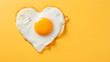 Fried delicious fried egg in the shape of a heart for Valentine's Day on a yellow background