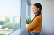 © baranq - Smiling young Asian woman looking out the window in modern office