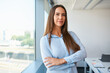 © baranq - Smiling adult businesswoman female entrepreneur looking at camera standing by the window at office