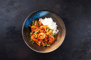 Wall Mural - Traditional Thai fried king prawns with vegetable, cashew nuts and rice served as top view in a design bowl with text space