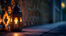 A Lit Lantern Sitting On The Ground Next To A Wall