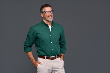 Wall Mural - Happy confident cool middle aged business man, smiling mature professional businessman wearing green shirt and stylish eyeglasses looking aside standing isolated on gray background.