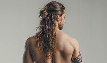 Athletic Back And Muscular Shoulders Of A Young Man With Long Hair On A Gray Background. Health And Sport Concept. Advertising Banner For A Fitness Studio. Background For A Sports Website.