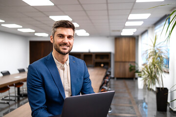 Competent company manager using laptop computer inside meeting room.