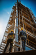 Construction workers working on scaffolding at a building site with blue sky