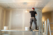 Professional painter in Santa hat applying plaster on wall for home renovation