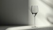  a wine glass sitting on a table with a shadow on the wall behind it and a shadow on the wall behind it that appears to be from the wine glass.