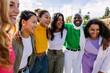 © Xavier Lorenzo - Happy young group of women laughing together outdoors. Female friendship concept with seven girls from different cultures bonding at city street.