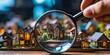© ParinApril - Hand holding a magnifying glass over miniature houses