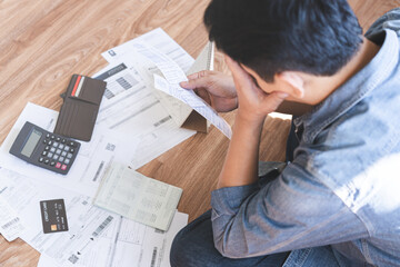 Canvas Print - Financial concept, owe asian young man sitting suffer, stressed and confused by calculate expense from invoice credit card bill, no money to pay mortgage or loan. Debt, bankrupt or bankrupt people.