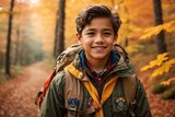 Fototapeta  - a boy scout with a backpack, standing on a rocky hill, looking out over a forest valley with a big smile on his face, International scout day concept 2024.