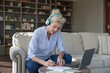 © fizkes - Focused mature woman e-learns using modern wireless tech, studying, gain knowledge, improve develop language skills, receive new knowledge, learning, planning use laptop and headphones. Self-education