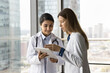 © fizkes - Multiethnic Indian and Caucasian doctor colleague women consulting electronic medical records on tablet together, using healthcare online service, application for communication, talking