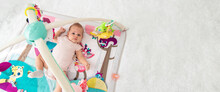 A Baby Plays With Hanging Toys On A Play Mat. A Child, A Baby Plays At Home