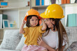 Asian mother and her daughter wearing yellow engineer helmet, education and occupation concept