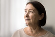 © fizkes - Serious pensive senior woman close up casual portrait with copy space. Thoughtful face of elderly female model looking at window away, daydreaming, thinking, pondering