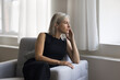 © fizkes - Attractive mature 50s blonde woman relaxing alone seated on cozy armchair, staring out window ponder, wait for husband, missing, deep in thoughts, search issue solution, looks pensive and thoughtful