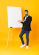 © luismolinero - Full-length shot of businessman giving a presentation on white board over isolated yellow background