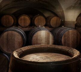 Sticker - Empty top of  wooden barrel and  wood barrels in cellar at the background. Sun ray falling down to it surface.