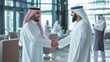 © Hope - Middle Eastern Business Partners Striking a Successful Deal at a Corporate Modern Meeting Room. Two Arab Men Shaking Hands, Managers in Traditional White Robes Celebrating and Clapping Hands