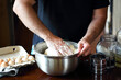 Male hands kneading fresh dough on the kitchen table