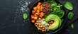 Top view of a black bowl with a salad of avocado, quinoa, roasted sweet potato, spinach, and chickpeas. Copy space available.