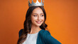  Beautiful young woman with princess crown on orange background