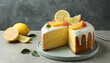 Cut tasty lemon cake with glaze and citrus fruits on light grey textured table, space for text