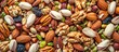 Top view of a mixture of nuts and dried fruits including pecans, pistachios, almonds, peanuts, cashews, and pine nuts.