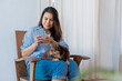 © kongga studio - Young woman have a break at work for making selfie with her domestic pet. Young Woman Using Smartphone With Her Dog At Home.