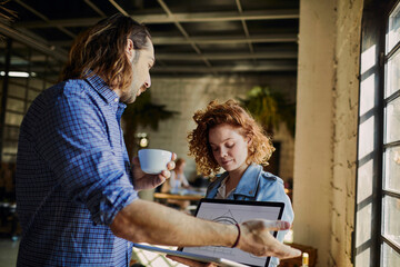 Wall Mural - Group of colleagues laughing and discussing project on laptop in a bright modern office