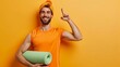 Young fitness trainer instructor sporty man sportsman wear orange t-shirt hold in hand yoga mat show thumb up training in home gym isolated on plain yellow background. Workout sport fit abs concept.