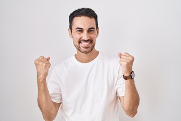 Sticker - Handsome hispanic man standing over white background celebrating surprised and amazed for success with arms raised and eyes closed. winner concept.