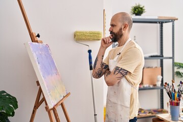 Canvas Print - Young bald man artist looking draw with serious expression at art studio