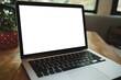 © Thaspol - Wooden table with laptop white screen complemented by a coffee shop blurred background.