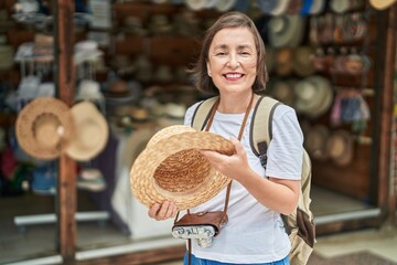 Canvas Print - Middle age woman tourist smiling confident holding hat at street market