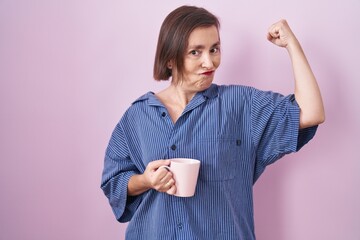 Canvas Print - Middle age hispanic woman drinking a cup coffee strong person showing arm muscle, confident and proud of power