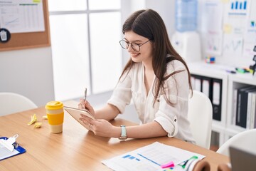 Wall Mural - Young caucasian woman business worker smiling confidnet writing on notebook at office