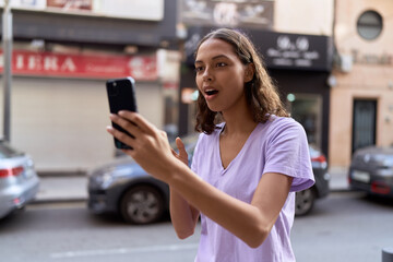 Wall Mural - Young african american woman using smartphone with surprise expression at street