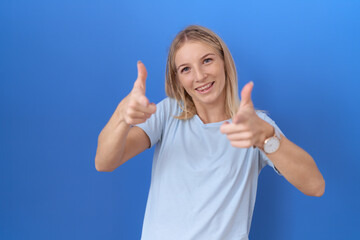 Poster - Young caucasian woman wearing casual blue t shirt pointing fingers to camera with happy and funny face. good energy and vibes.