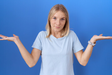 Sticker - Young caucasian woman wearing casual blue t shirt clueless and confused expression with arms and hands raised. doubt concept.