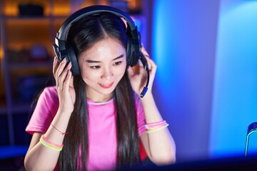 Canvas Print - Young chinese woman streamer smiling confident sitting on bed at gaming room