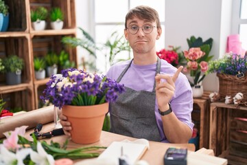 Poster - Caucasian blond man working at florist shop pointing aside worried and nervous with forefinger, concerned and surprised expression