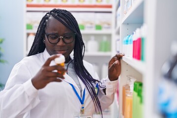 Sticker - African american woman pharmacist holding pills bottle on shelving at pharmacy