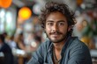 © create - Portrait of a young man with curly hair smiling in a cafe with soft bokeh background.