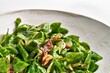 Closeup of a fresh mache salad with walnuts and vinaigrette dressing served on a ceramic plate.
