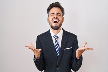 Poster - Young hispanic man with tattoos wearing business suit and tie celebrating mad and crazy for success with arms raised and closed eyes screaming excited. winner concept