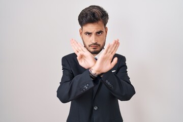 Sticker - Young hispanic man with tattoos wearing business suit and tie rejection expression crossing arms and palms doing negative sign, angry face