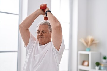 Poster - Middle age grey-haired man using dumbbell training at home